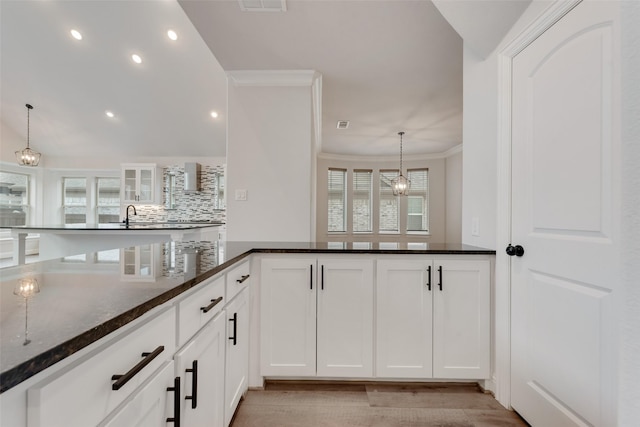 kitchen featuring decorative light fixtures, plenty of natural light, dark stone counters, and white cabinets