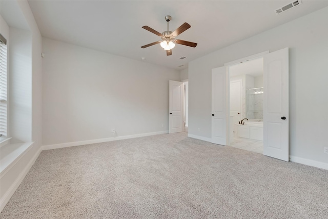 unfurnished bedroom with ceiling fan, light colored carpet, and connected bathroom