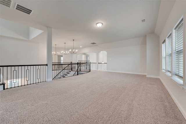 carpeted empty room with a chandelier