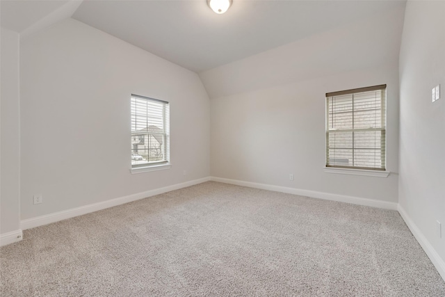 carpeted spare room with vaulted ceiling