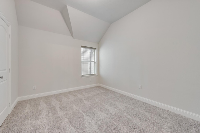 carpeted empty room with vaulted ceiling