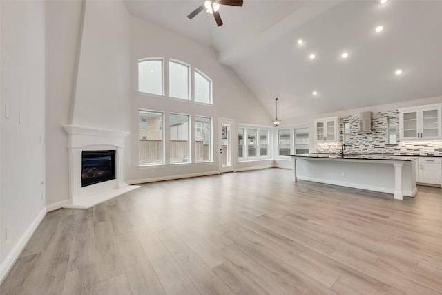 unfurnished living room with sink, ceiling fan, and light hardwood / wood-style flooring