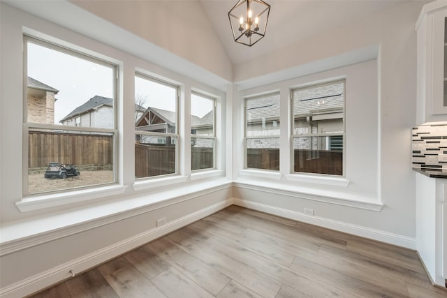 unfurnished dining area with lofted ceiling, light hardwood / wood-style floors, and an inviting chandelier