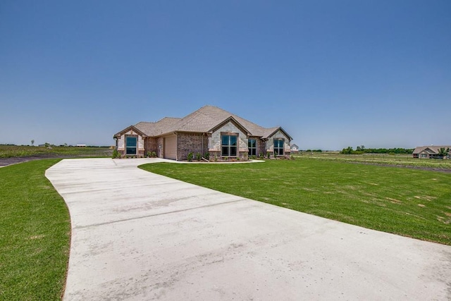 view of front of house with a garage, a front yard, stone siding, and concrete driveway