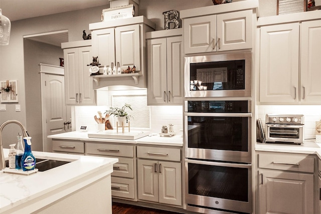 kitchen with stainless steel double oven, a sink, built in microwave, and tasteful backsplash