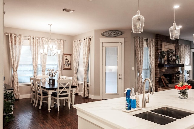 kitchen featuring a sink, baseboards, light stone counters, dark wood-style floors, and a chandelier