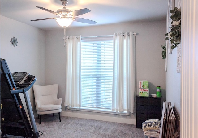 sitting room with a ceiling fan and carpet