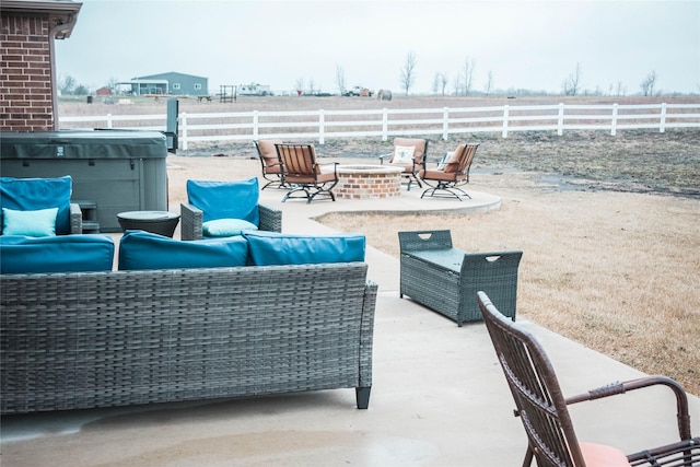 view of patio / terrace with a hot tub, fence, and an outdoor living space with a fire pit