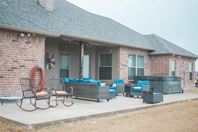 back of property featuring an outdoor hangout area, a patio area, roof with shingles, and brick siding