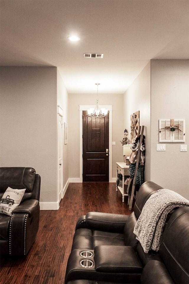 living room featuring visible vents, baseboards, wood finished floors, and a notable chandelier