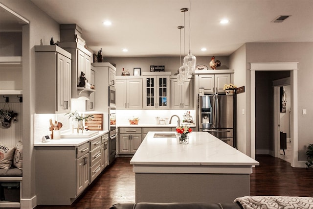 kitchen featuring a sink, a kitchen island with sink, stainless steel appliances, recessed lighting, and gray cabinetry