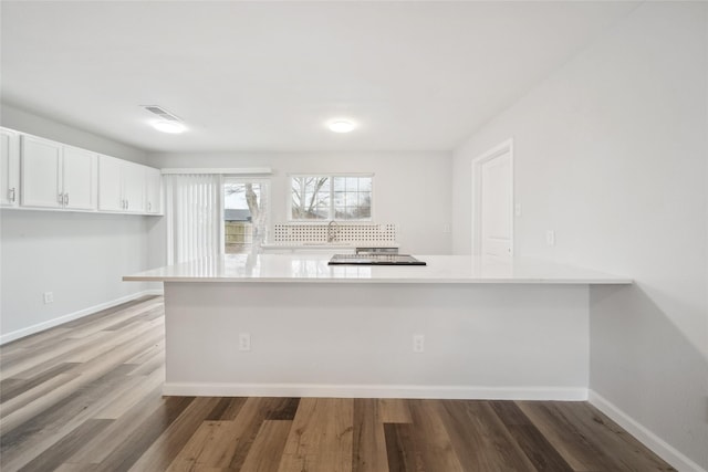 kitchen with hardwood / wood-style flooring, white cabinets, and kitchen peninsula