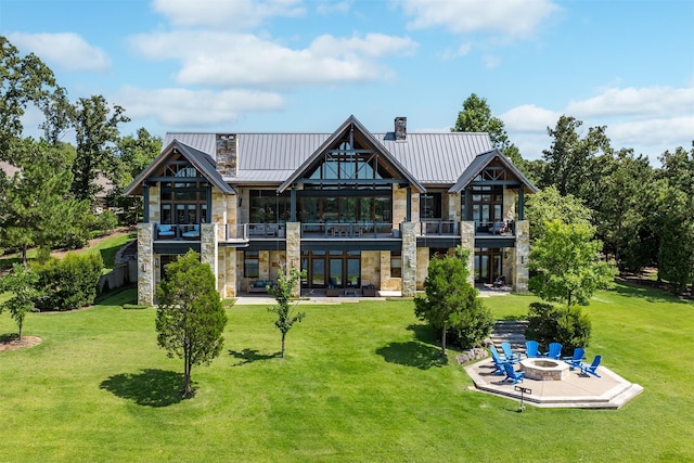 rear view of house featuring a fire pit, a patio area, and a lawn