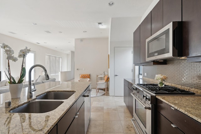 kitchen featuring sink, light stone counters, light tile patterned floors, stainless steel appliances, and decorative backsplash