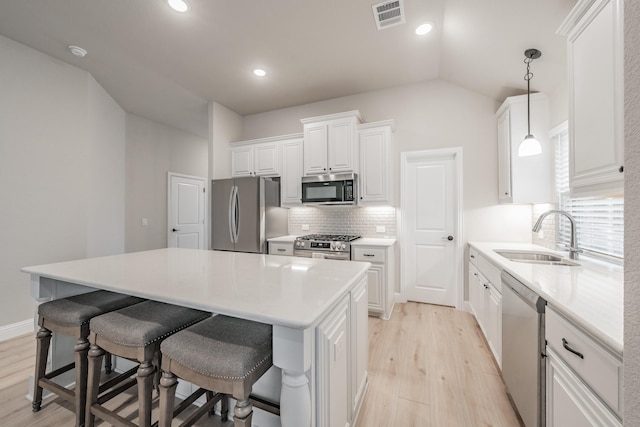 kitchen with a sink, visible vents, white cabinets, appliances with stainless steel finishes, and a center island