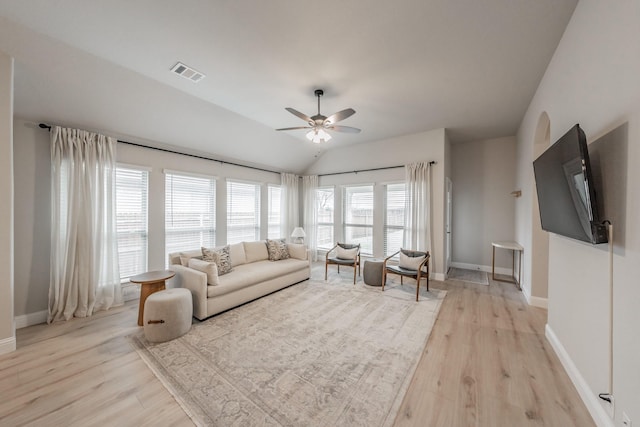 living room featuring ceiling fan, visible vents, baseboards, vaulted ceiling, and light wood-type flooring