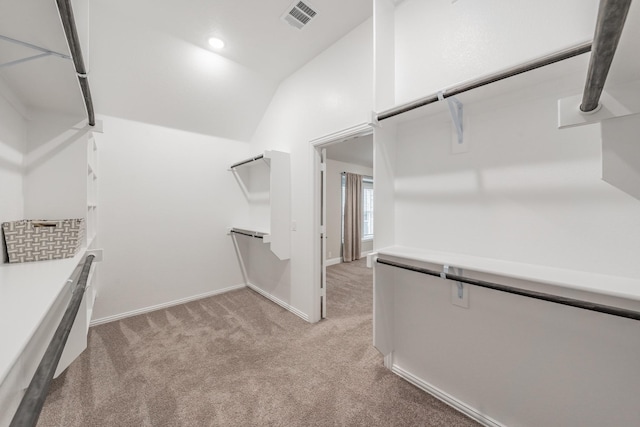 spacious closet featuring light carpet, visible vents, and lofted ceiling