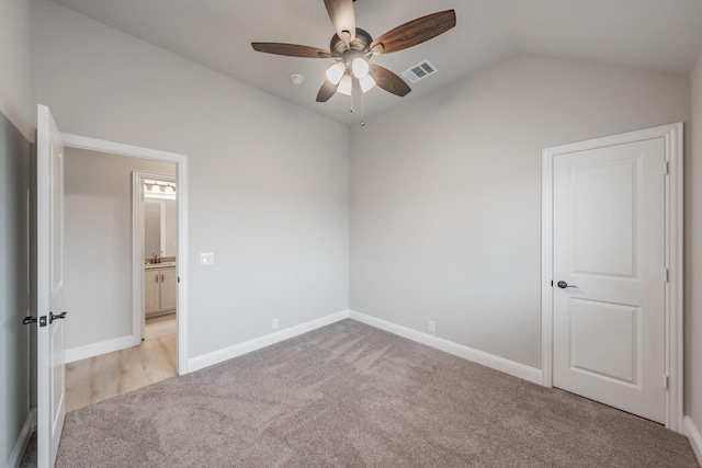 unfurnished bedroom featuring visible vents, a ceiling fan, light carpet, vaulted ceiling, and baseboards