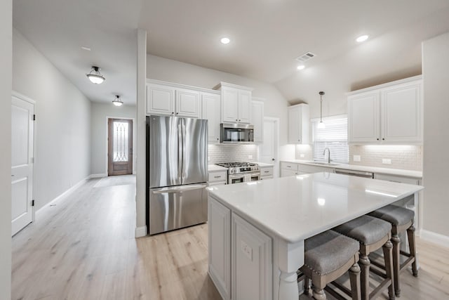 kitchen featuring light wood-style flooring, a sink, visible vents, appliances with stainless steel finishes, and a center island