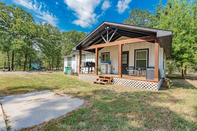 rear view of house featuring a yard and a porch