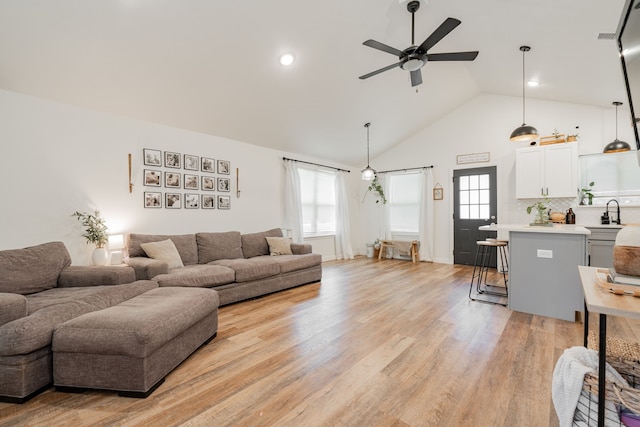 living room with sink, high vaulted ceiling, ceiling fan, and light wood-type flooring