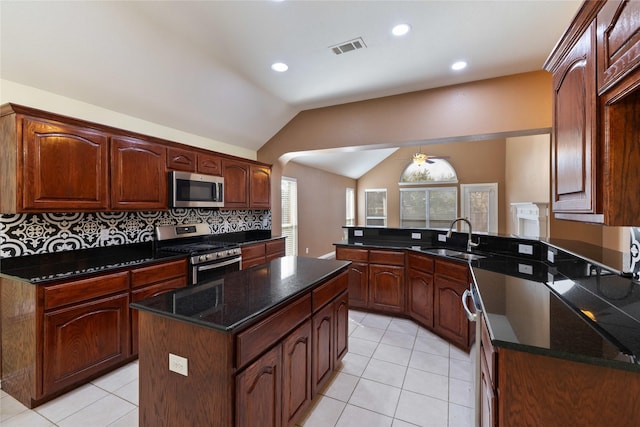 kitchen featuring appliances with stainless steel finishes, lofted ceiling, sink, a center island, and light tile patterned floors