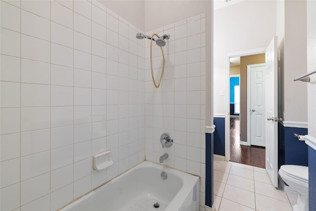 bathroom featuring tile patterned flooring, toilet, and tiled shower / bath