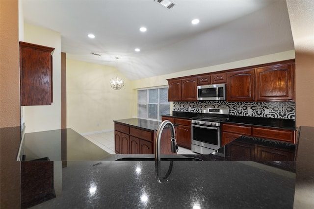 kitchen with lofted ceiling, sink, decorative light fixtures, stainless steel appliances, and decorative backsplash