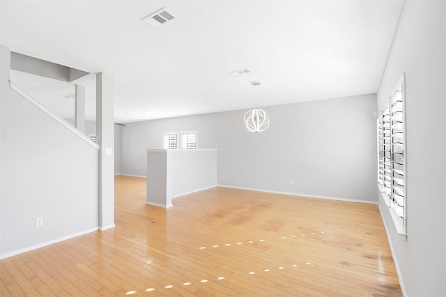 unfurnished room with an inviting chandelier and light wood-type flooring