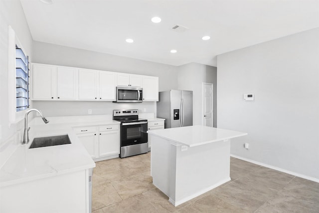 kitchen with white cabinetry, sink, stainless steel appliances, and a kitchen island