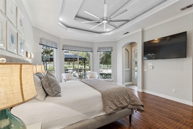 bedroom with crown molding, ceiling fan, wood-type flooring, and a raised ceiling