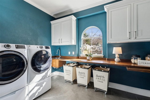 laundry area featuring sink, crown molding, cabinets, light tile patterned floors, and washing machine and dryer