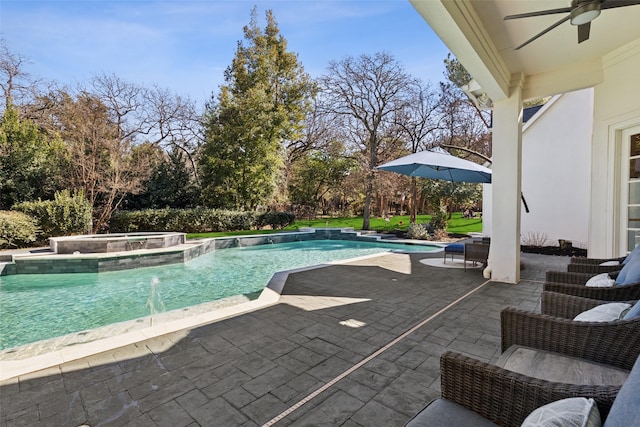 view of swimming pool with a patio, pool water feature, ceiling fan, and an in ground hot tub