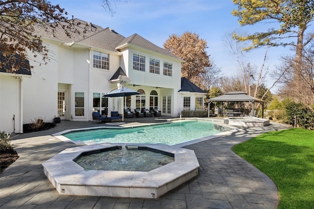 back of property featuring a swimming pool with hot tub, a gazebo, outdoor lounge area, and a patio