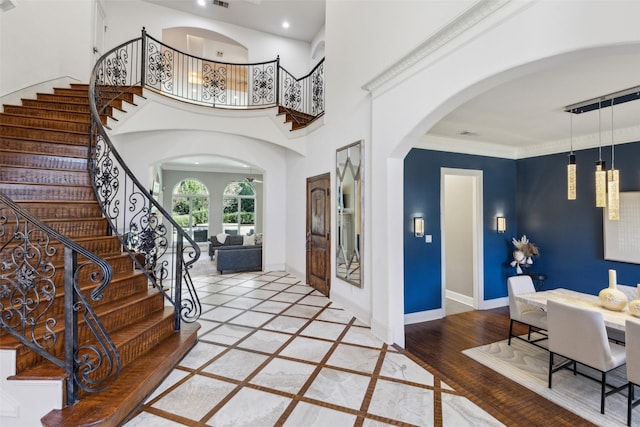 entryway featuring hardwood / wood-style flooring, a towering ceiling, and ornamental molding