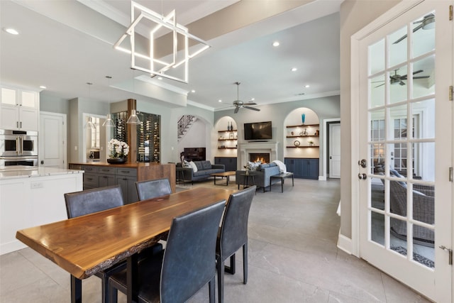 dining room with crown molding, ceiling fan with notable chandelier, and built in features