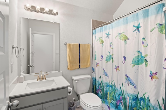 bathroom featuring lofted ceiling, vanity, toilet, and curtained shower