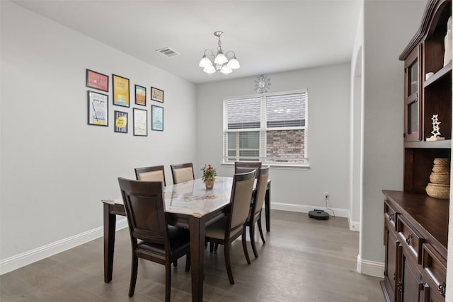 dining space with hardwood / wood-style floors and a chandelier