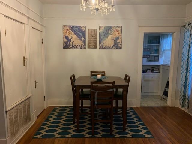 dining area featuring dark wood-type flooring and an inviting chandelier