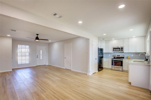 kitchen featuring stainless steel appliances, light hardwood / wood-style floors, sink, and white cabinets