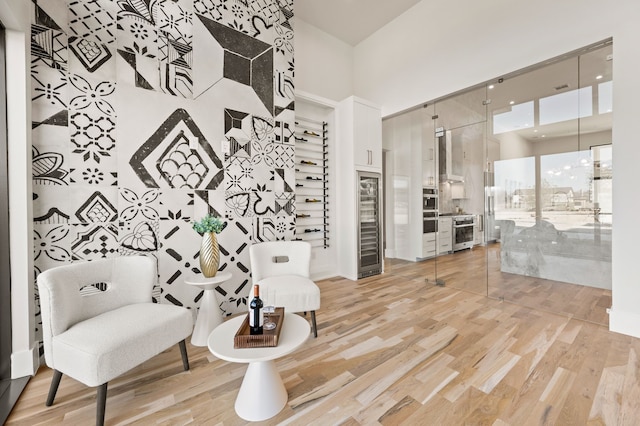 sitting room with a towering ceiling and light hardwood / wood-style flooring