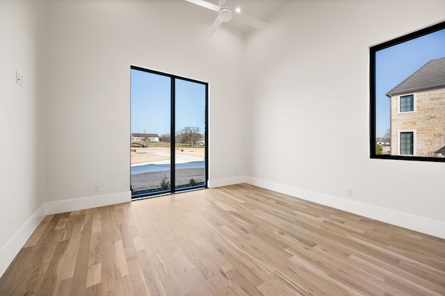 spare room featuring a towering ceiling, light hardwood / wood-style flooring, and ceiling fan