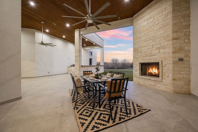 dining room featuring wood ceiling, a large fireplace, and ceiling fan