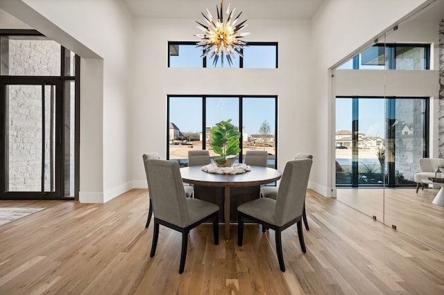 dining area featuring an inviting chandelier, light hardwood / wood-style flooring, and a high ceiling