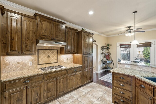 597 Imagine Dr, Lindale, TX 75771 - kitchen featuring tasteful backsplash, ornamental molding, stainless steel gas cooktop, light tile patterned floors, and light stone countertops