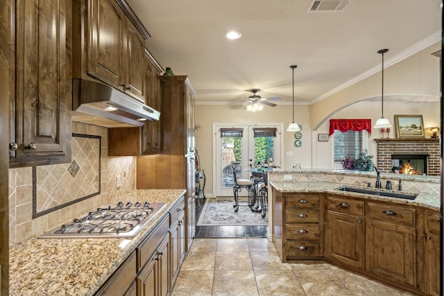 597 Imagine Dr, Lindale, TX 75771 - kitchen with sink, light stone counters, crown molding, hanging light fixtures, and stainless steel gas stovetop