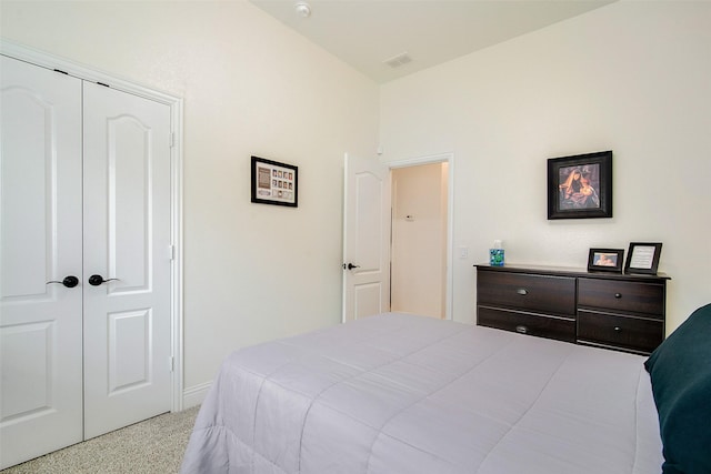 bedroom featuring light carpet, vaulted ceiling, and a closet