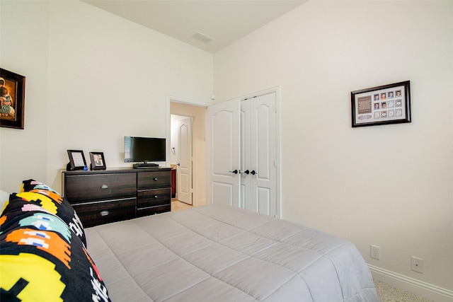 carpeted bedroom with a towering ceiling and a closet