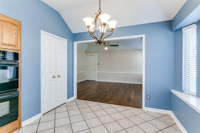 unfurnished dining area with vaulted ceiling, light tile patterned floors, and an inviting chandelier