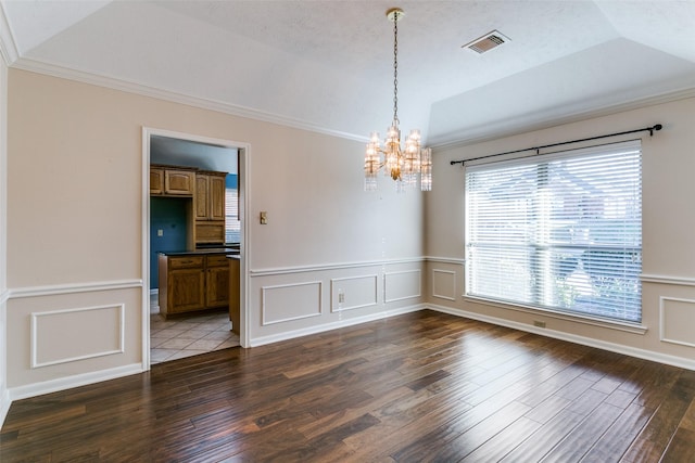 empty room with dark hardwood / wood-style flooring, a textured ceiling, ornamental molding, and a chandelier